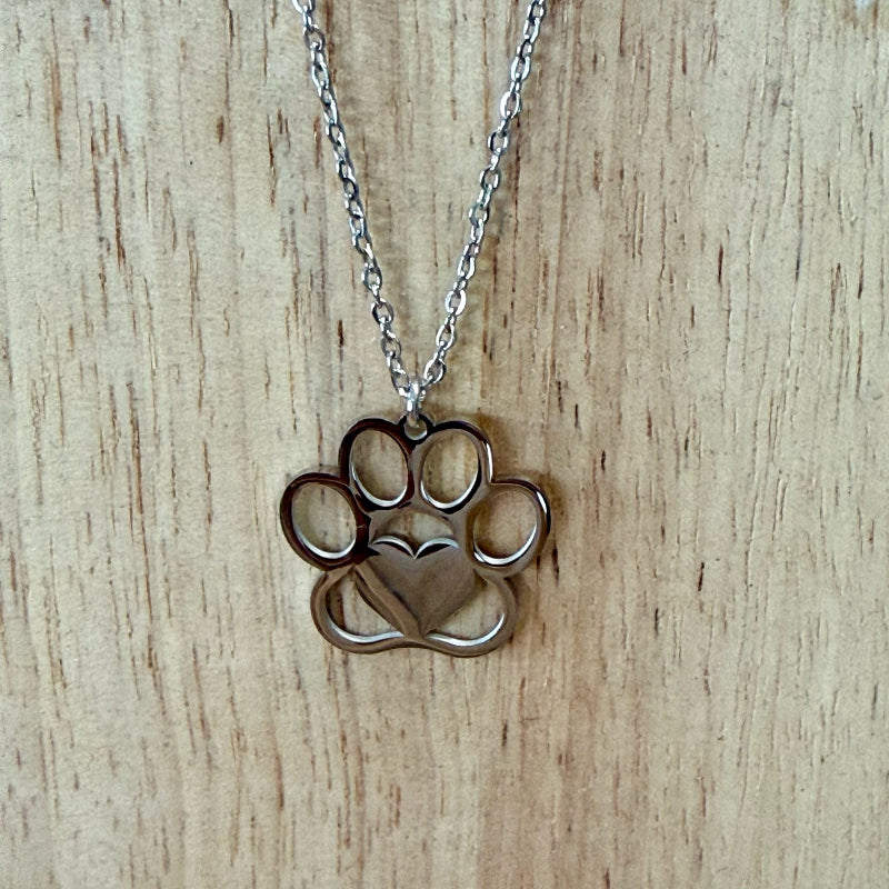 Necklace with a paw print and heart pendant on a wooden surface