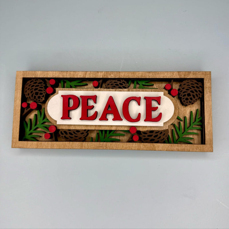 Decorative sign with 'PEACE' text surrounded by Christmas-themed elements on a plain background