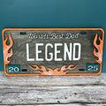 A novelty license plate sign with a wooden background, black and orange text that reads 'WORLD'S BEST DAD LEGEND', and orange flame designs.