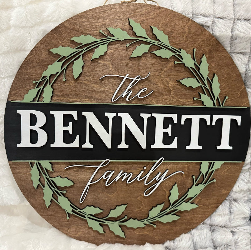 Round wooden sign with 'The Bennett Family' text and green leaf design on a white textured background