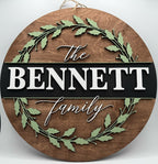 Wooden circular sign with 'The BENNETT Family' text and leaf designs on a white background