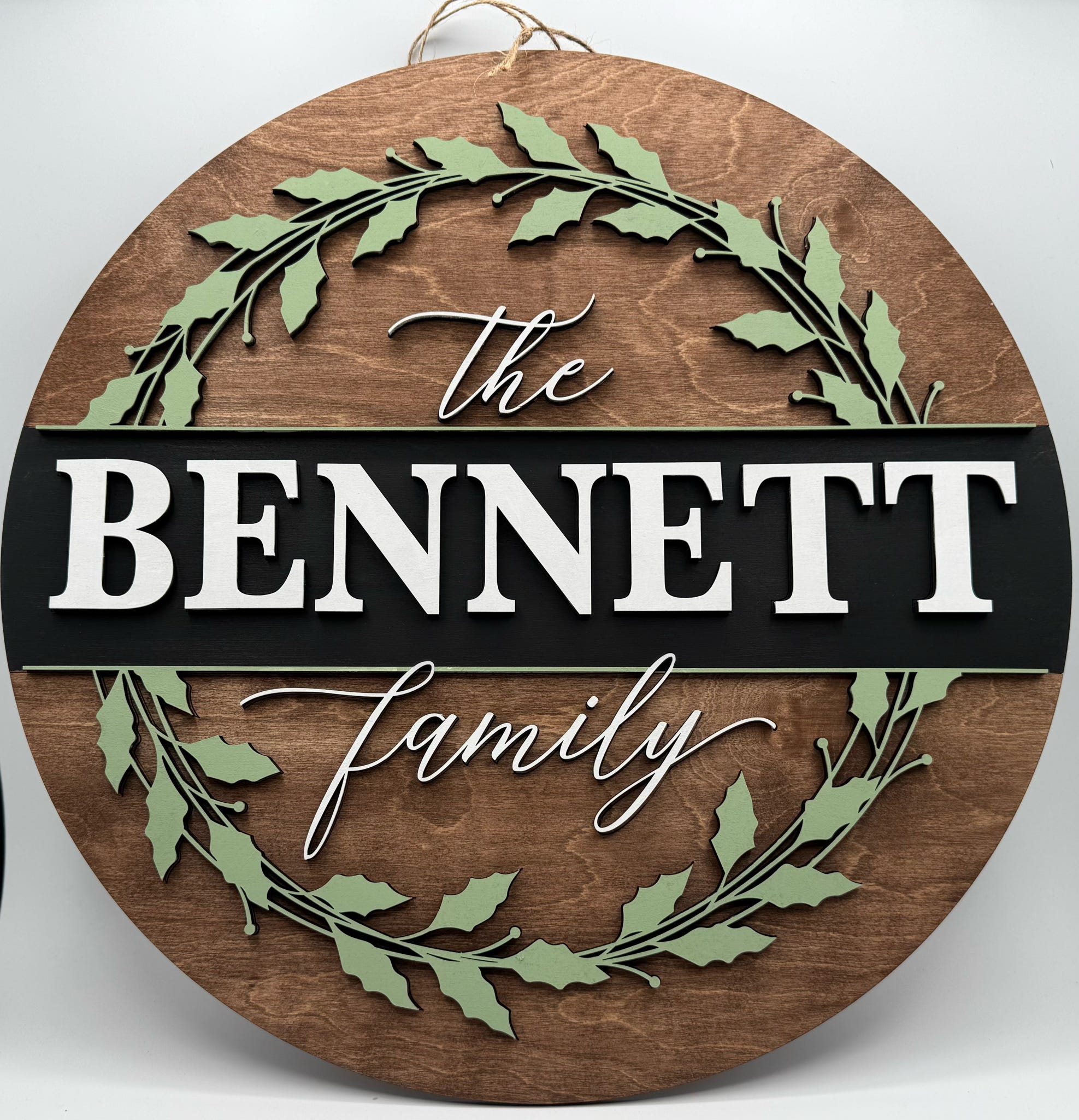 Wooden circular sign with 'The BENNETT Family' text and leaf designs on a white background
