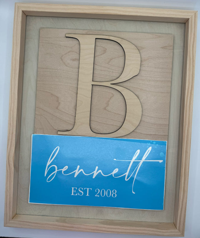 Wooden cutout of a logo with a blue card displaying 'Bennell' and 'Est. 2008' on a light gray background.