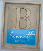 Wooden cutout of a logo with a blue card displaying 'Bennell' and 'Est. 2008' on a light gray background.