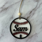 Decorative ornament shaped like a baseball with 'Sam' on a marble background