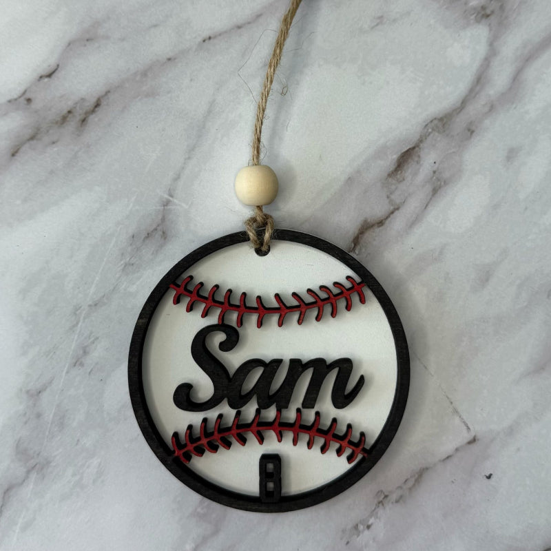 Decorative ornament shaped like a baseball with 'Sam' on a marble background