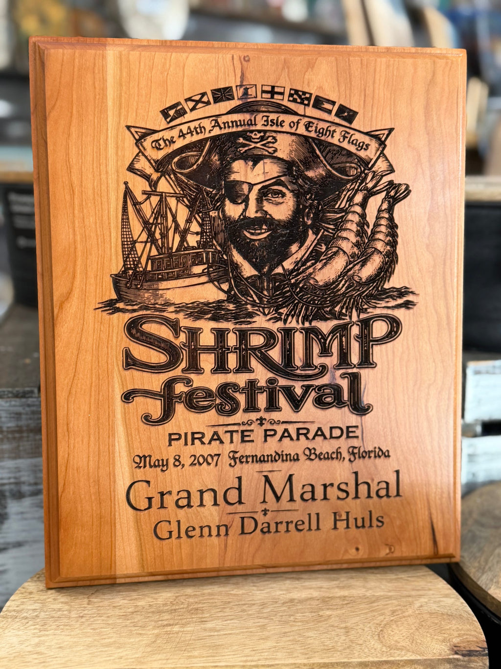 A personalized wooden plaque featuring an engraved pirate illustration and the text  with custom names and dates, displayed on a wooden surface.