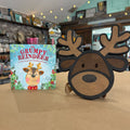 A wooden Christmas-themed standee shaped like a reindeer head with antlers stands next to a children's book titled 'The Grumpy Reindeer' on a tabletop in a shop setting.