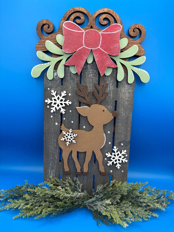 Decorative wooden panel with reindeer, bow, and snowflakes on a blue background