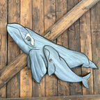 Metal whale sculpture on a wooden wall