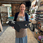 Woman holding a large black bird sculpture in a store setting