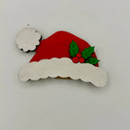 Decorative Christmas ornament with a red Santa hat, white beard, and holly leaves on a light gray background.