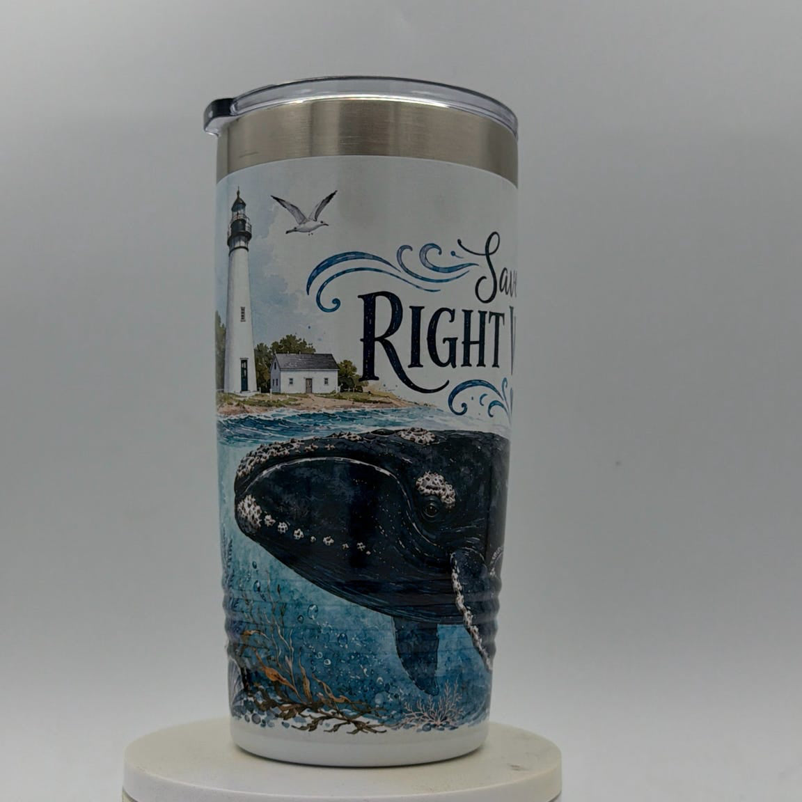 Tumbler with a design of a whale and lighthouse on a white background