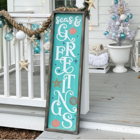 Decorative sign with 'Seas & Greetings' on a porch with Christmas decorations. Fernandina Beach DIY Craft Party.