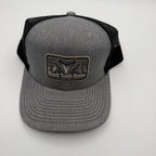 A gray and black trucker hat with a front patch reading 'Shark Tooth Hunter' and a shark fin graphic, photographed on a light gray background.