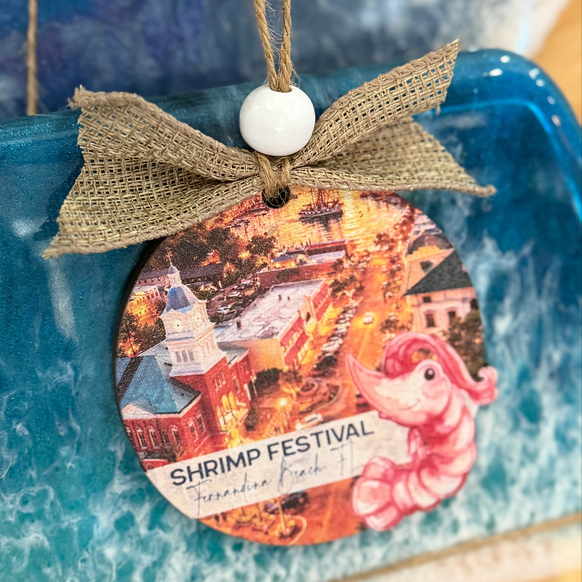 Decorative ornament with a shrimp festival design on a blue textured background