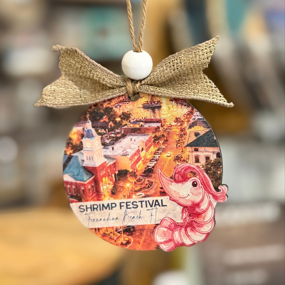 Decorative ornament with a shrimp festival design and burlap bow on a blurred background