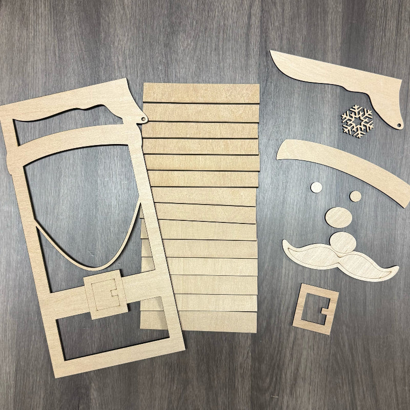 Wooden cutouts of decorative items including a shield, slats, and facial features on a wooden surface.
