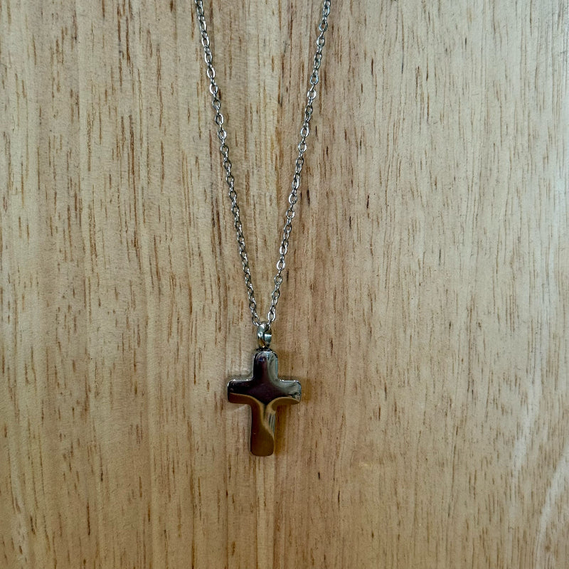 Silver necklace with a cross pendant on a wooden surface