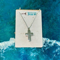 Silver cross necklace on a branded card with a blue ocean background