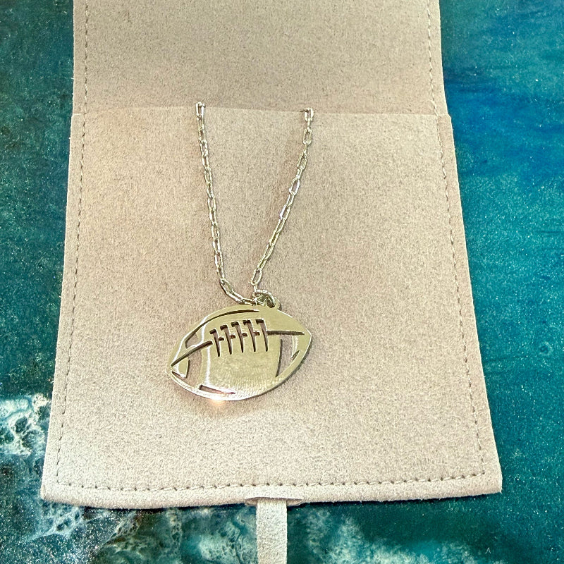 Silver football-shaped pendant necklace on a beige card with a blue textured background
