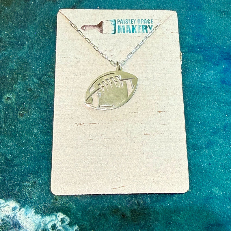 Necklace with football pendant on a card with 'Paisley Grace Design' branding against a teal background.