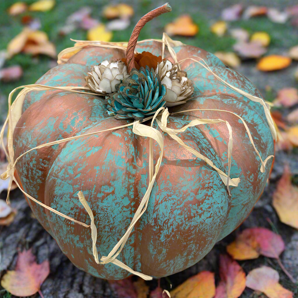 Decorative pumpkin with turquoise patina and decorative elements on a table.