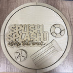 Wooden decorative sign with 'Splash & Splash! We're Out Back' text and pool-themed cutouts on a wooden surface.