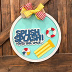 Decorative sign with 'Splash Splash! We're Out to Rock' text and beach-themed items on a wooden background.