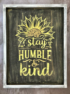 A wooden frame sign with a sunflower design and the text 'stay HUMBLE & kind'.