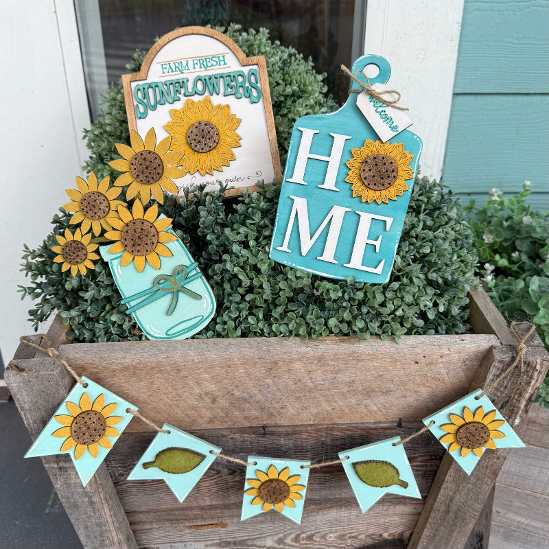 Decorative sunflower-themed signs and bunting in a wooden planter.