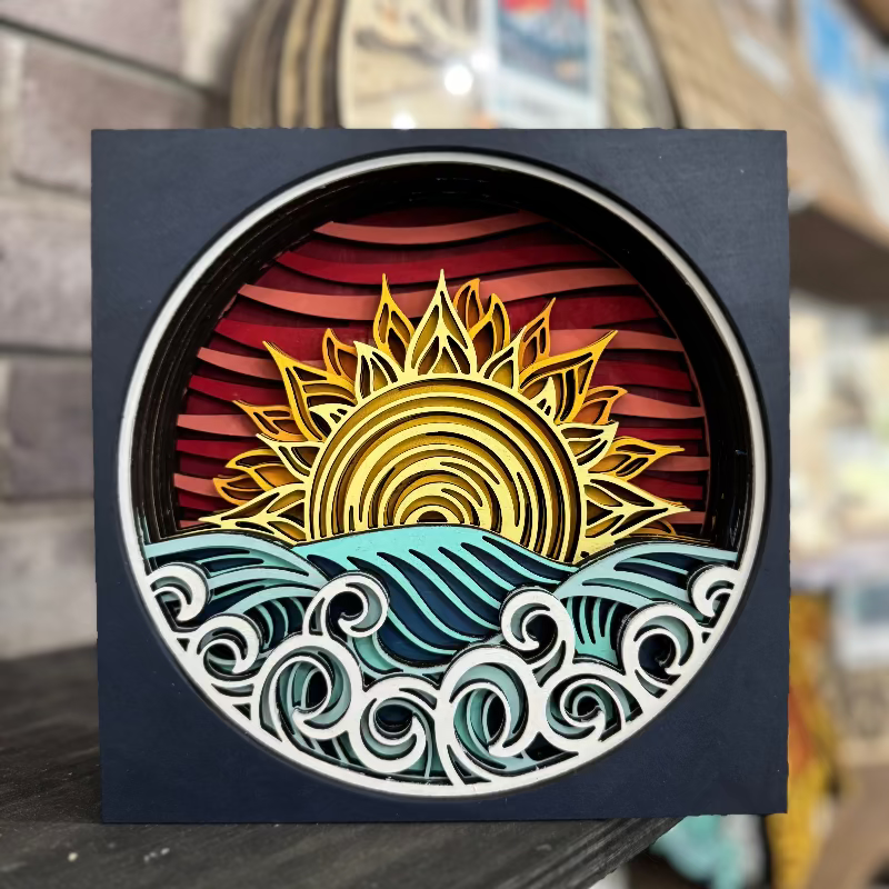 Decorative wall art with a sun and wave design on a black background.
