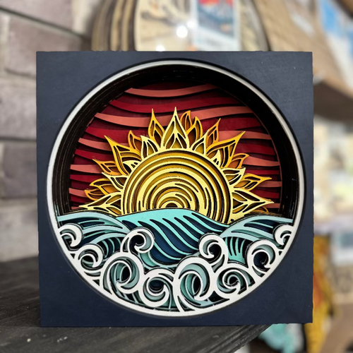Decorative wall art with a sun and wave design on a black background.