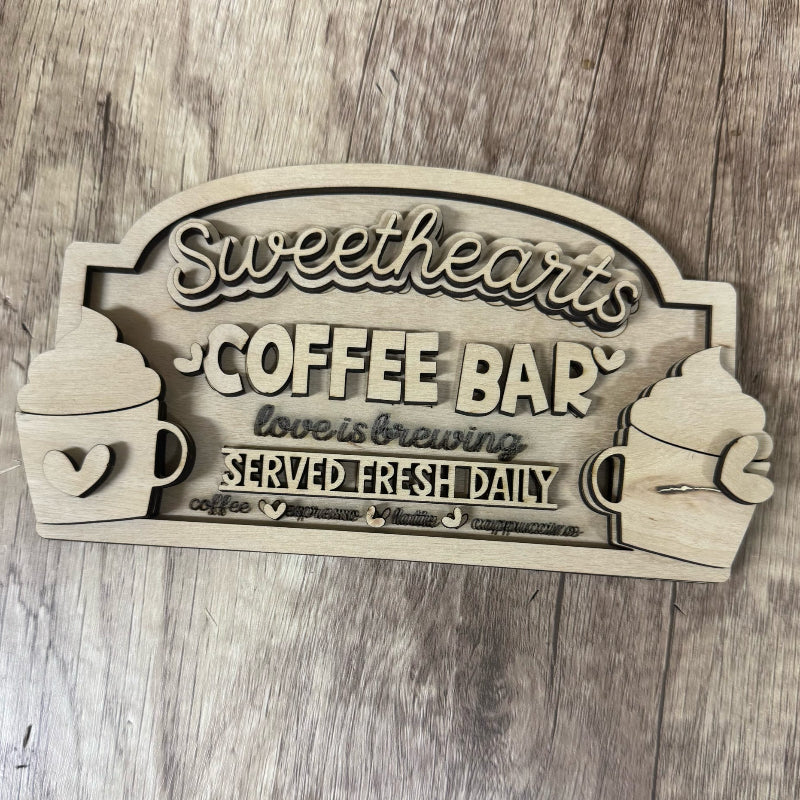 Wooden sign with 'Sweethearts Coffee Bar' text on a wooden surface
