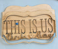 Wooden sign with 'This Is Us' and names on a blue background