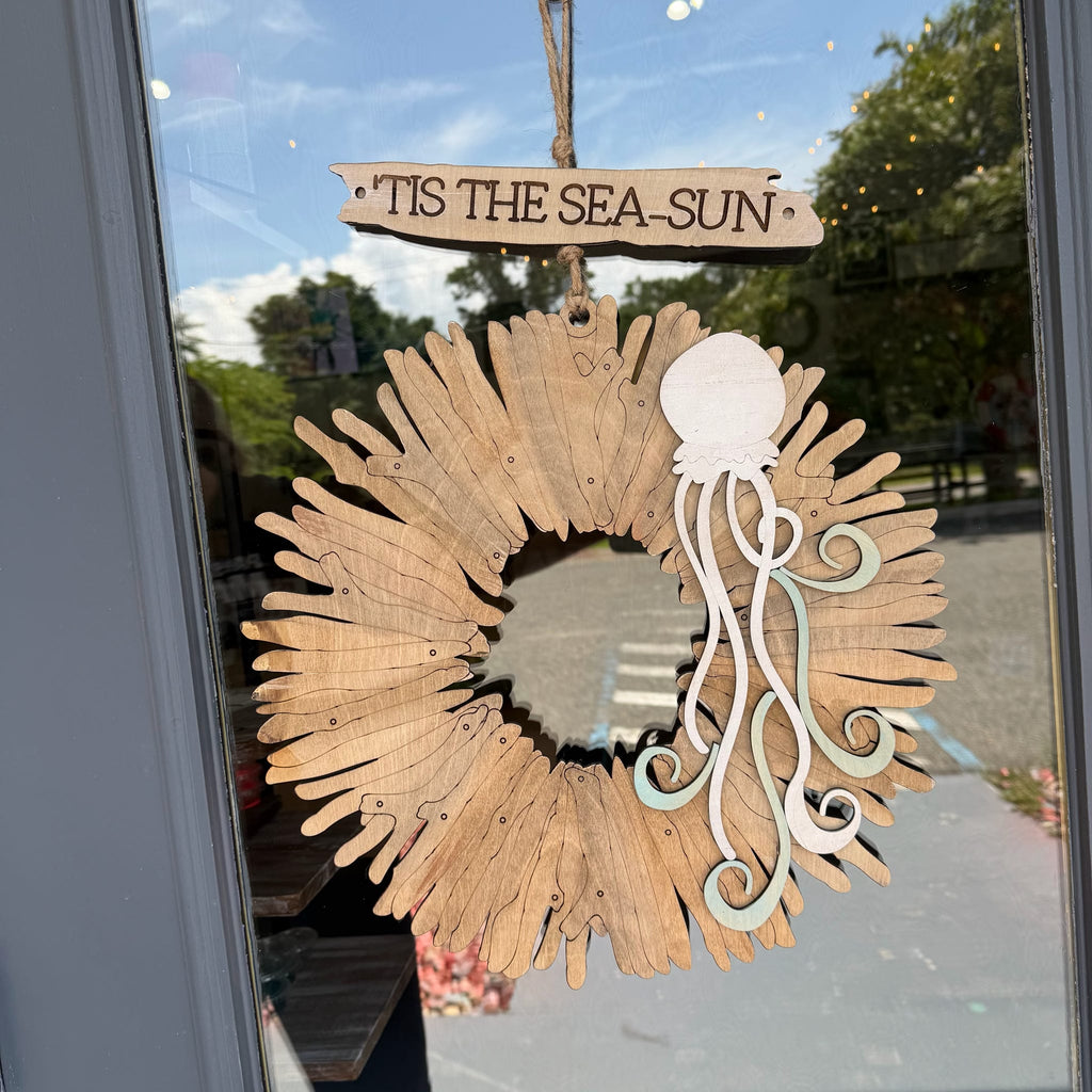 A rustic wooden octopus decoration hanging on a glass door. The octopus is made from natural wood splinter pieces with a white and pale green octopus head and tentacles.