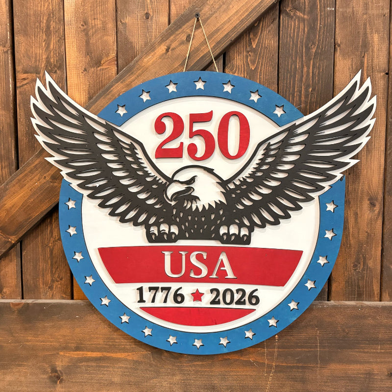 Decorative sign with an eagle and '250 USA 1776-2026' text on a wooden background