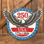Decorative sign with an eagle and '250 USA 1776-2026' text on a wooden background