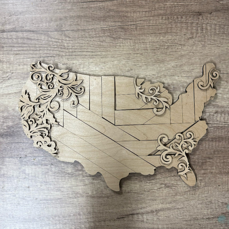 Wooden wall art in the shape of the United States with decorative cutouts on a wooden surface.