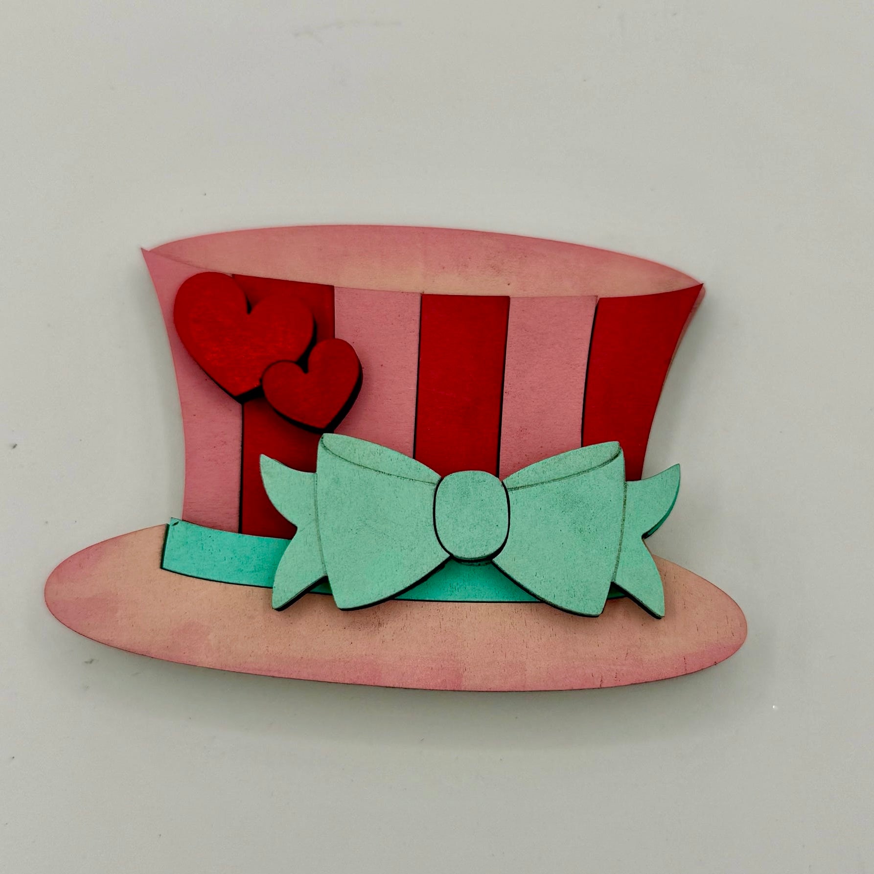 Colorful top hat with red and pink stripes and a green bow on a white background