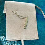 Necklace with a pendant on a beige pouch against a blue textured background