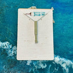 Necklace with a rectangular pendant on a branded card against a blue water background