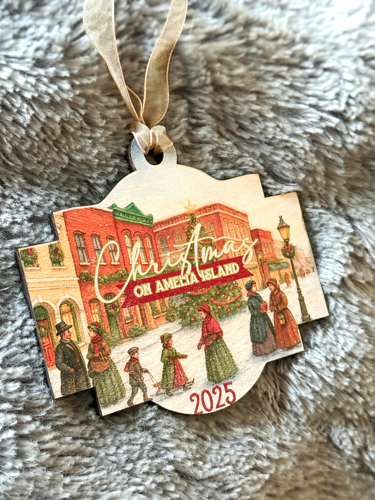 Decorative Christmas ornament with 'Christmas on Amelia Island' text and vintage-style buildings on a textured surface.