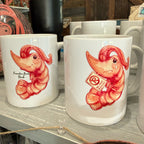 Two white mugs with a red character design on a wooden surface.