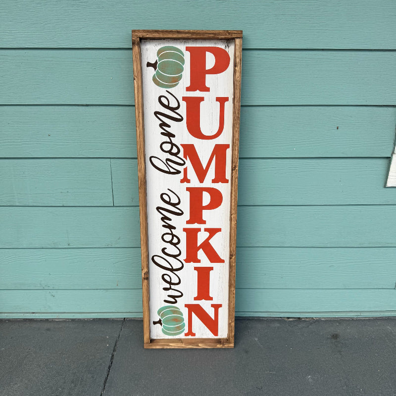 Decorative sign with 'Welcome Home Pumpkin' text against a teal wooden wall.