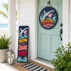 Decorative signs for 'Shark Week' on a door with plants and lanterns.