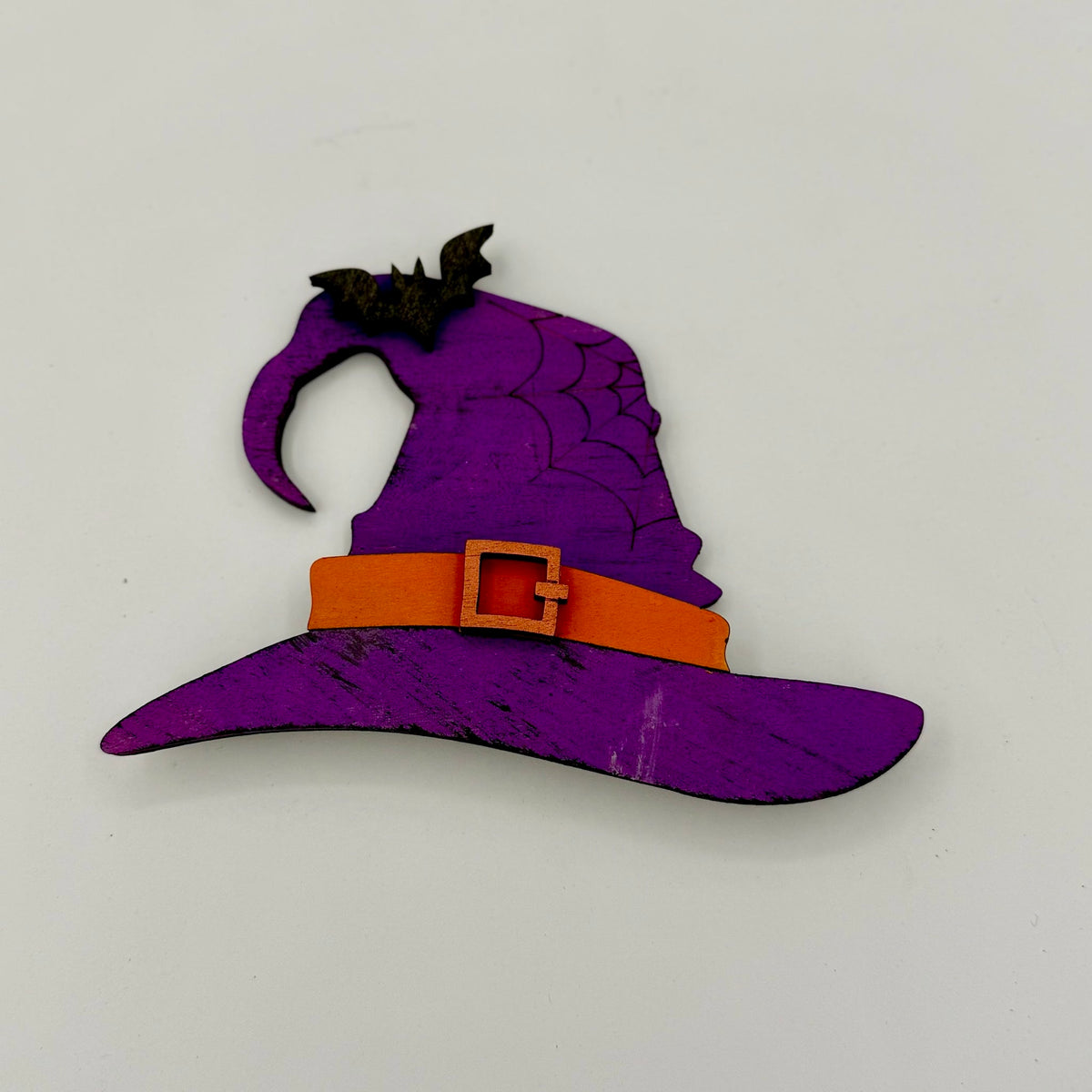 Purple witch hat with an orange belt on a light gray background