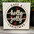 Have a Holly Jolly Christmas framed sign beside greenery in white, green and red