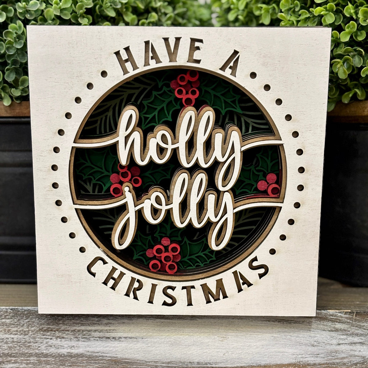 Have a Holly Jolly Christmas framed sign beside greenery in white, green and red