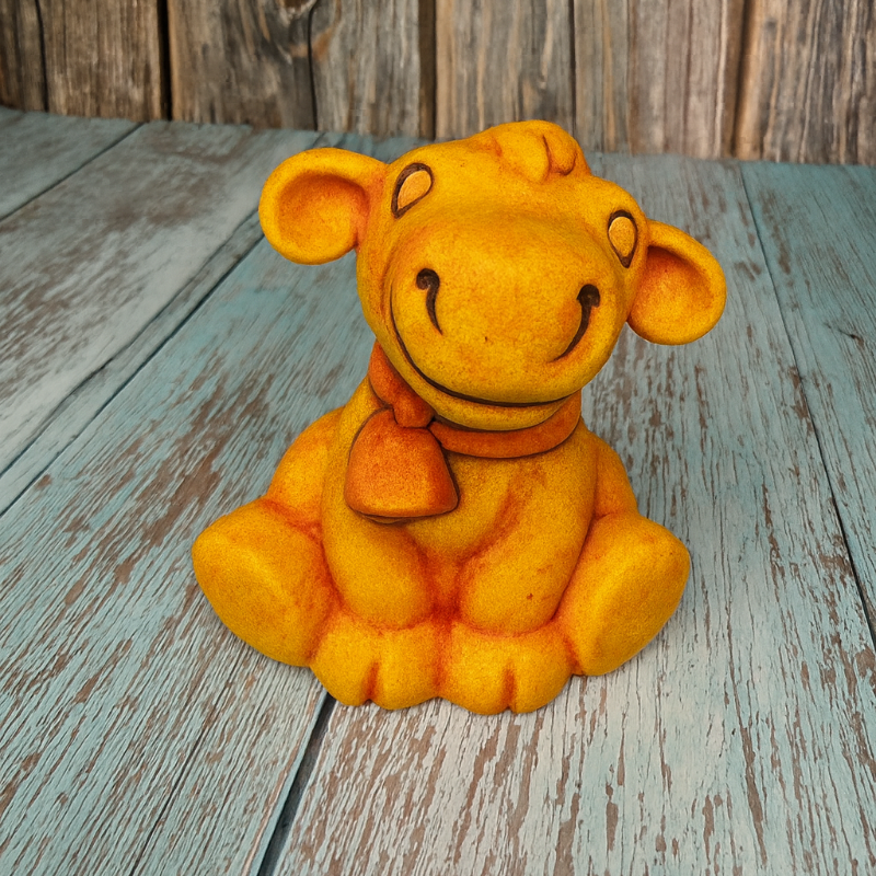 Yellow plush toy bear sitting on a wooden surface with a rustic background